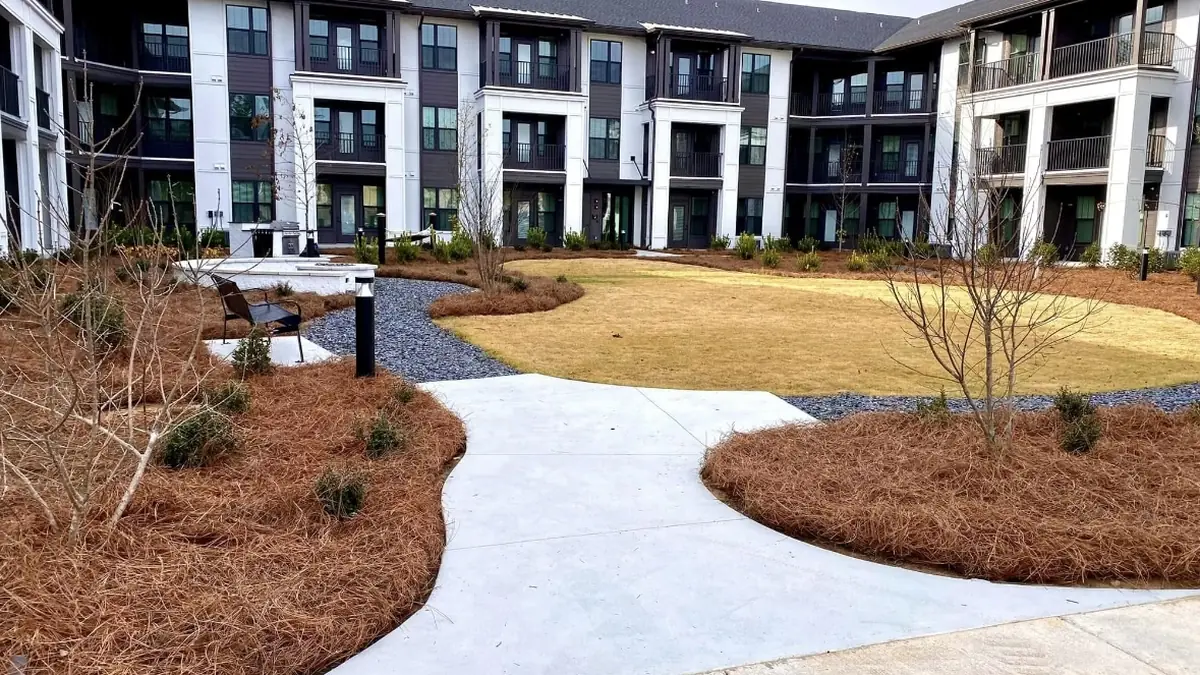 Beds either side of the walk Freshly strawed courtyard beds by Luckie's Pinestraw curve along a wide apartment walkway
