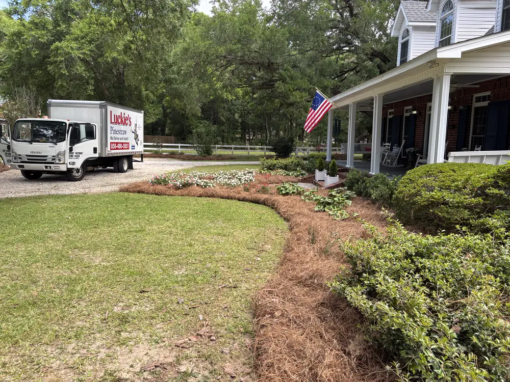 Company box truck on the gravel drive beside a crisp new bed line and flag-hung porch